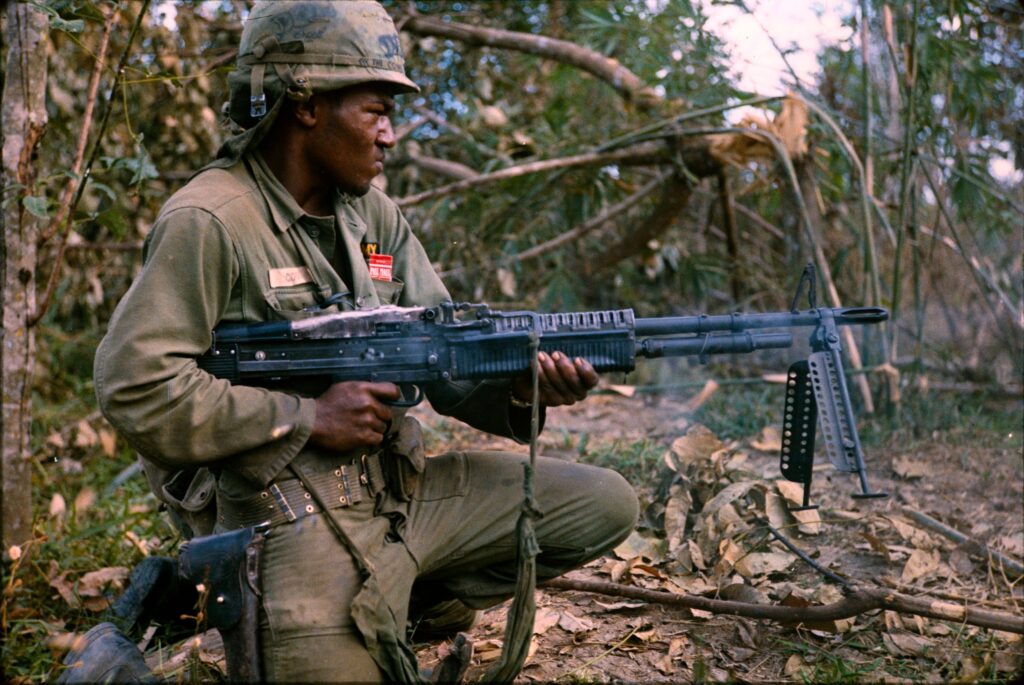 25th Infantry Division soldier Private First Class Milton Cook spraying a tree line with M60 fire during Operation Cedar Falls in 1967.